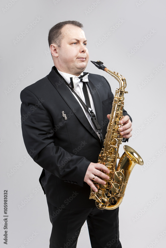 Fototapeta premium Man with Saxophone in Suite Posing Against White Background.