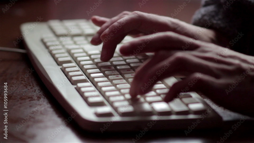 dark keyboard working/working with his hands on a white keyboard in a dark room dark keyboard working/working with his hands on a white keyboard in a dark room