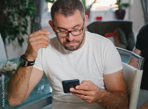 young man with glasses looks at the phone