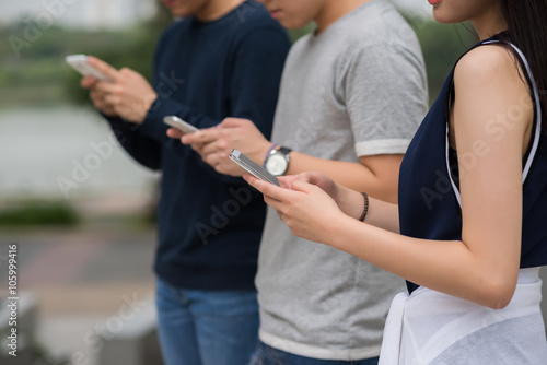 Group of young people using smartphones when standing outdoors