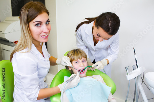 Young handsome dentist treats tooth child  a woman dentist