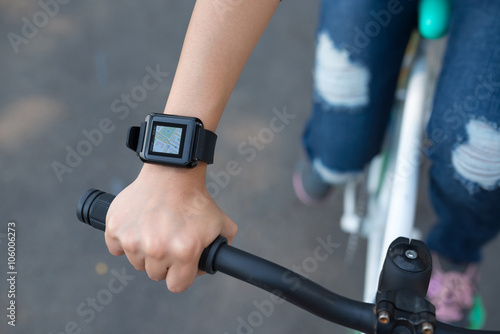 Girl riding bicycle with map in her smart watch © DragonImages