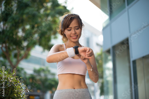 Beautiful female jogger checking smart watch when running © DragonImages