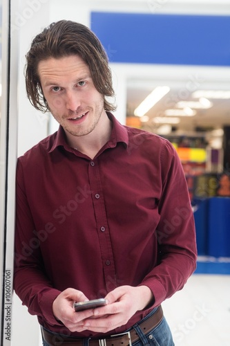 Portrait of man using a mobile phone outside a shop