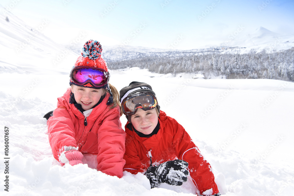 Kids at ski resort laying down in snow