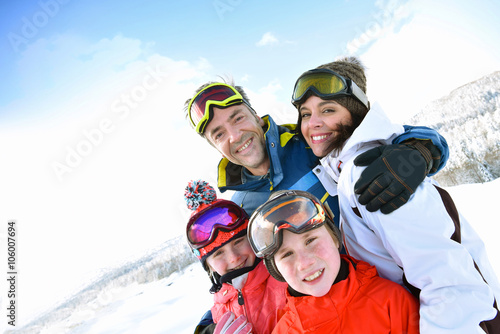 Portrait of happy family of 4 in snowy mountains
