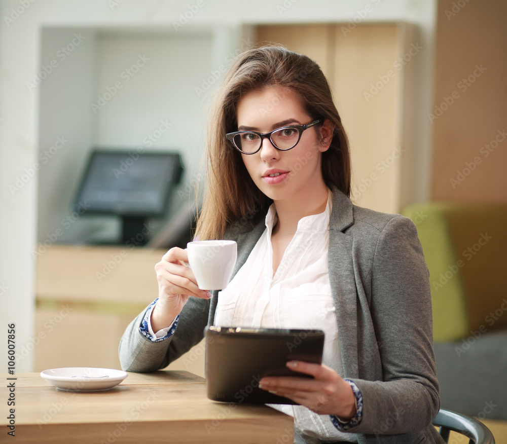 Young business woman with a cup of coffee working in office Young business woman with a cup of coffee working in office