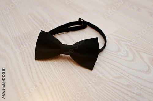 Black cotton bow tie on light wooden background