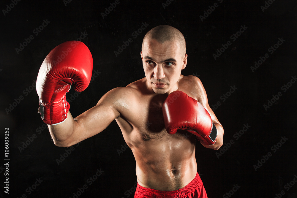 The young man kickboxing on black