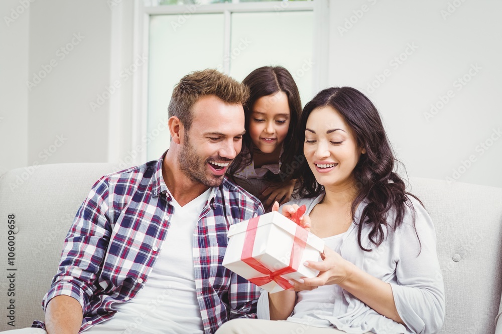 Parents and daughter looking at gift box Parents and daughter looking at gift box