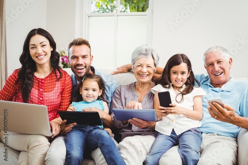 Portrait of happy family holding technologies at home