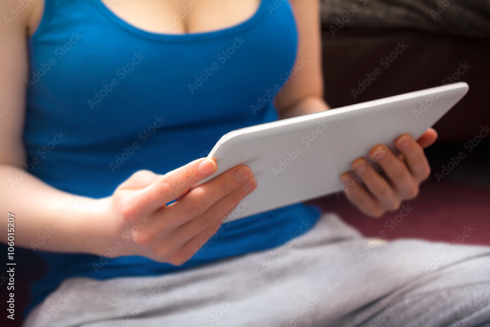 Busty Woman In Blue Tank Top Holding A White Business Tablet In Her Hands