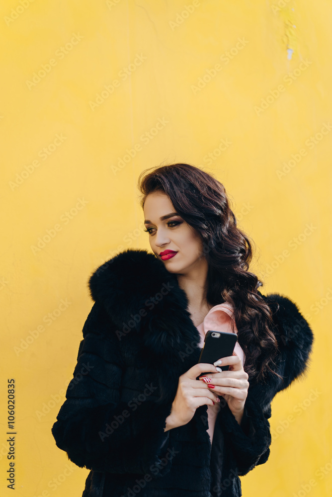 Beautiful girl with the phone on a yellow background