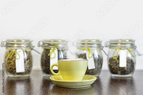 tea in glass jars and cup on wooden table with white background