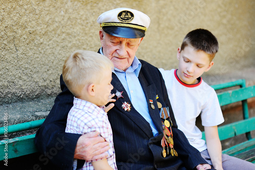 WWII veteran with children. Grandchildren looking at grandfather photo