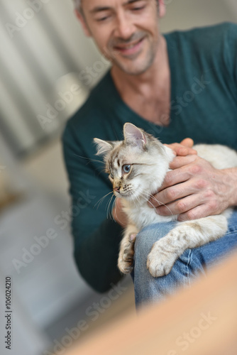 Man at home cuddling beautiful cat