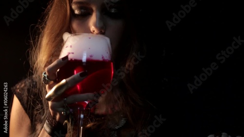 A mystic woman blowing liquid smoke above a glass of red wine photo