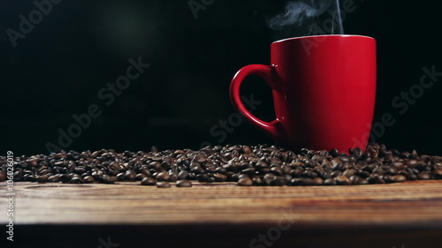 cup with hot drink on roasted coffee beans.