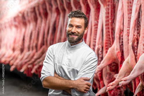 фотографія Portrait of a handsome butcher in white uniform at the meat manufacturing with p