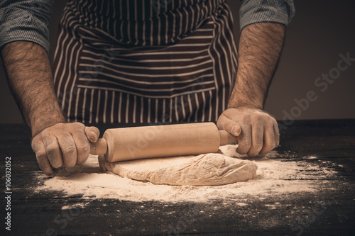 Male hands knead the dough.