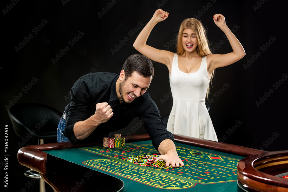 Young couple celebrating win at roulette table in casino. Young couple celebrating win at roulette table in casino.