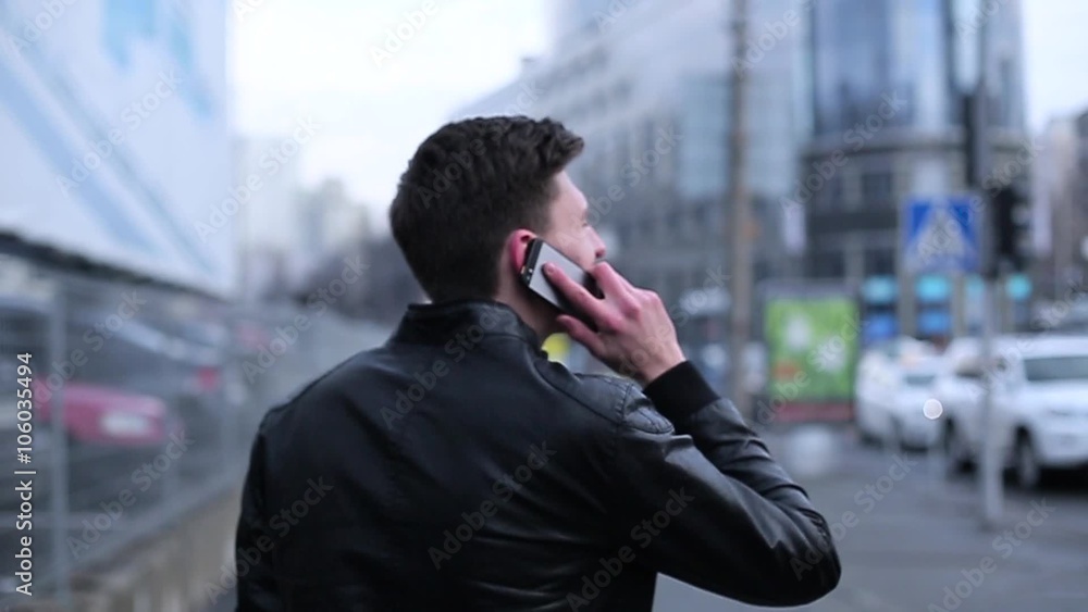 Man brunette talking on a cell going through the city. Man brunette talking on a cell going through the city.