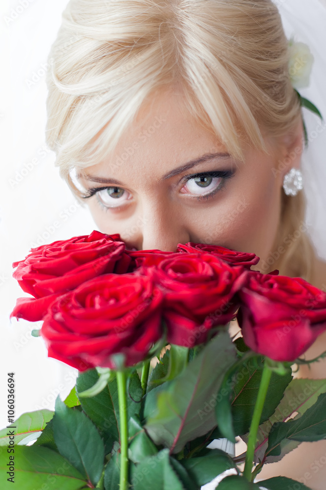 Portrait of a charming bride with beautiful smile and red lipstick, looking up ,with a bouquet of red roses Portrait of a charming bride with beautiful smile and red lipstick, looking up ,with a bouquet of red roses