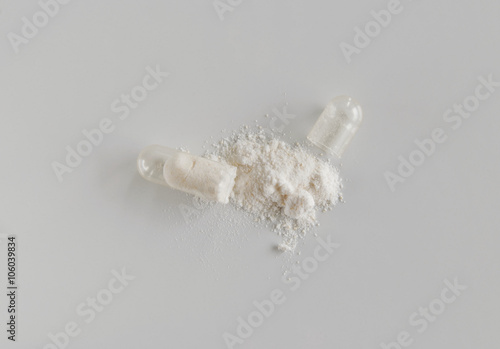 Single open medicine capsule with white probiotic powder.
