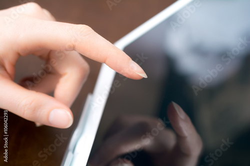 Female Hand Touches A White Business Tablet Computer On A Holder