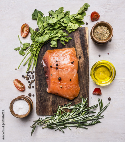 ece of smoked salmon on a cutting board with herbs and spices on wooden rustic background top view photo