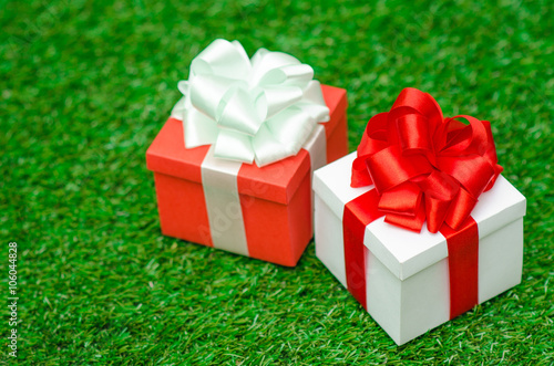 Gifts and congratulations topic: two beautiful boxes with gifts lying on green grass in summer