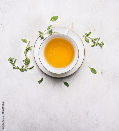 tea with thyme in a white cup on a white saucer place for text on wooden rustic background top view