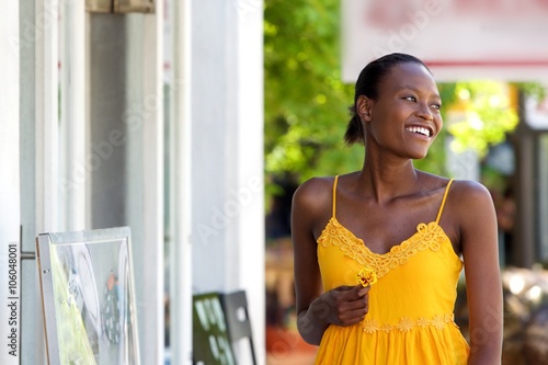 Attractive african woman walking outdoors with flower