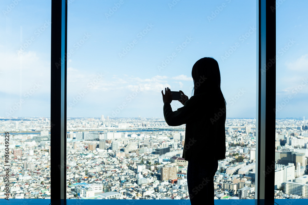 Fototapeta premium Silhouette of woman taking photo on Tokyo city