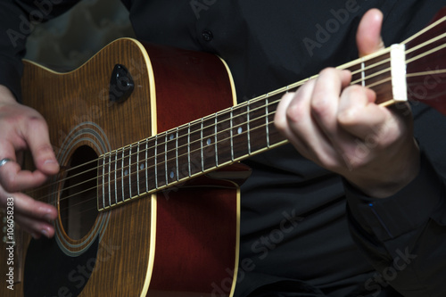 Closeup of man's hands playing on guitar