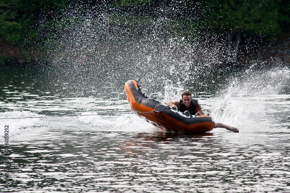 Adult male tubing on a lake.