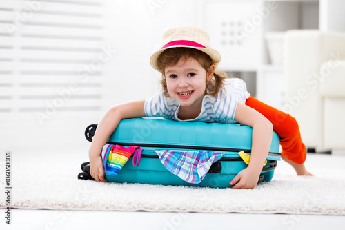 happy child girl packs clothes into suitcase for travel, vacatio photo