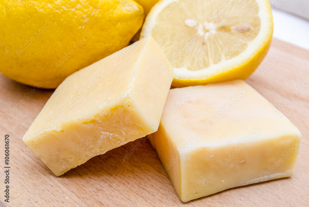Traditional lemon scented home made soap in a close view on a wood board with a sliced lemon on the background