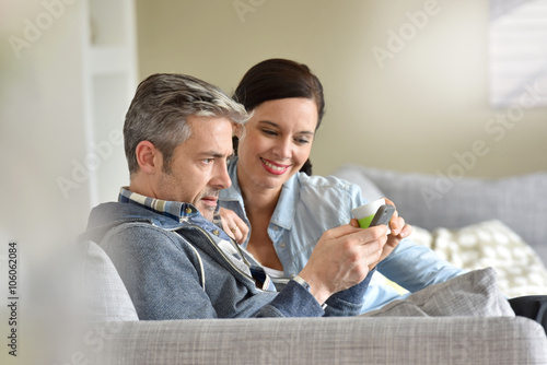 Middle-aged couple relaxing in sofa at thome photo