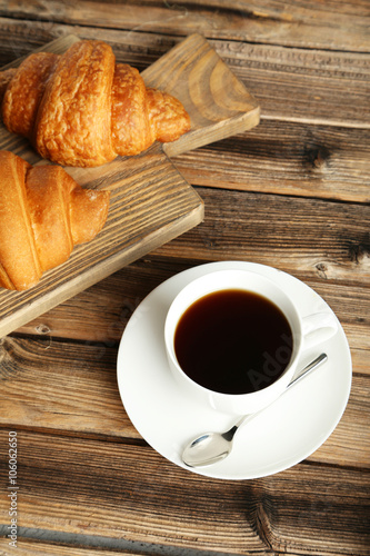 Fototapeta Naklejka Na Ścianę i Meble -  Tasty croissants with cup of coffee on brown wooden background
