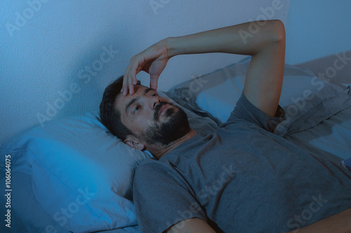 sleep disorder, insomnia. young beard man lying on the bed awake