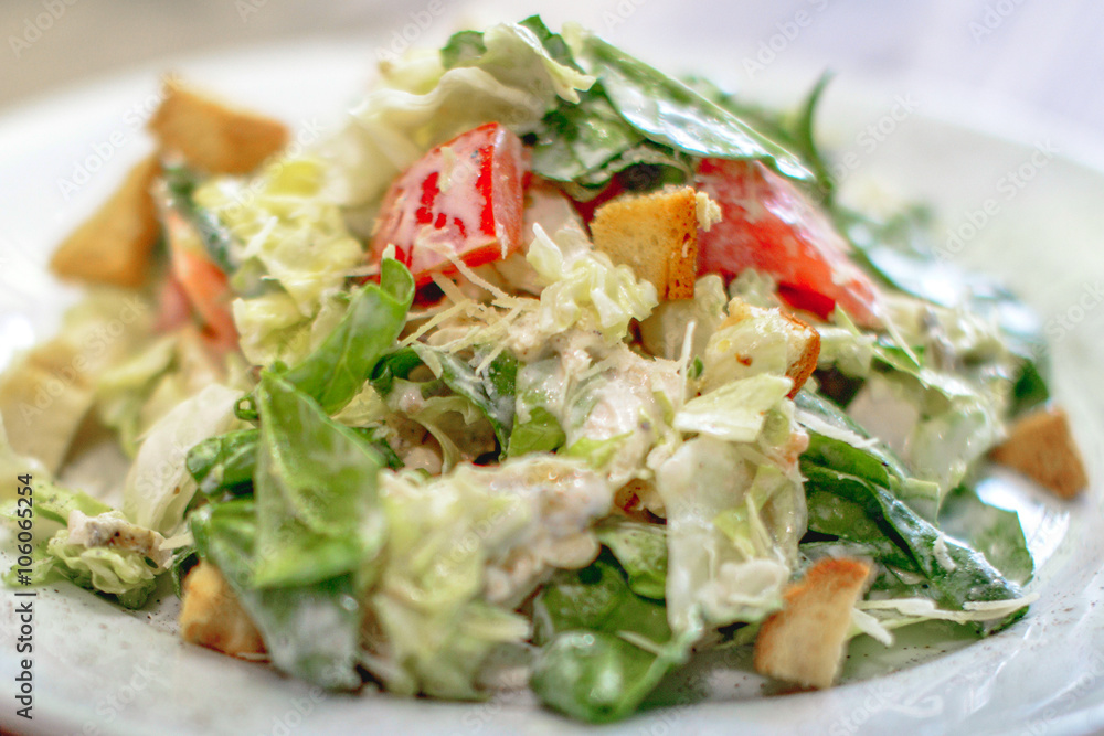 Caesar salad with chicken and greens on wooden table