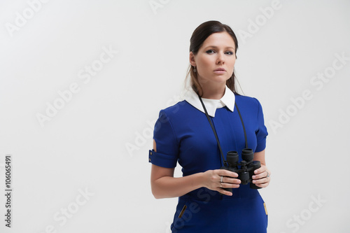 Girl in a blue suit. Keep a binoculars in his hands. Makes gestu photo