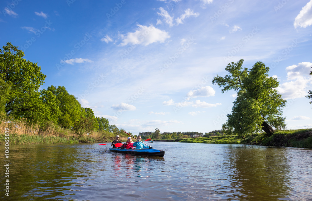 Naklejka premium Young people are kayaking on a river in beautiful nature. Summer sunny day