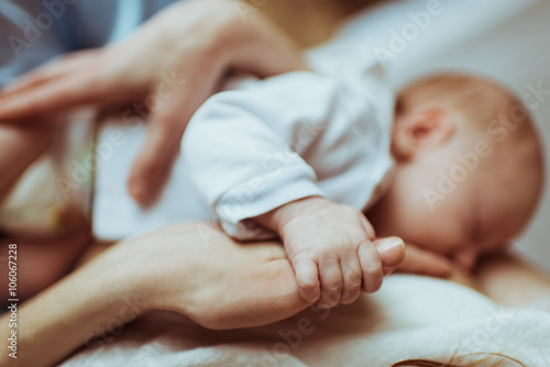 mother breastfeeds her infant , the baby holds hand of mother's hand
