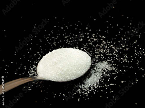 Spoon full of sugar on black background