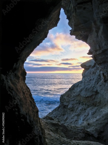  A colorful sunset sky framed by natural arch at Sunset Cliffs, Point Loma, California