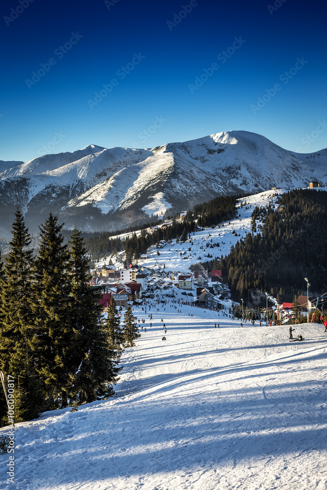 View down of a snowy ski slope in alpine mountain valley