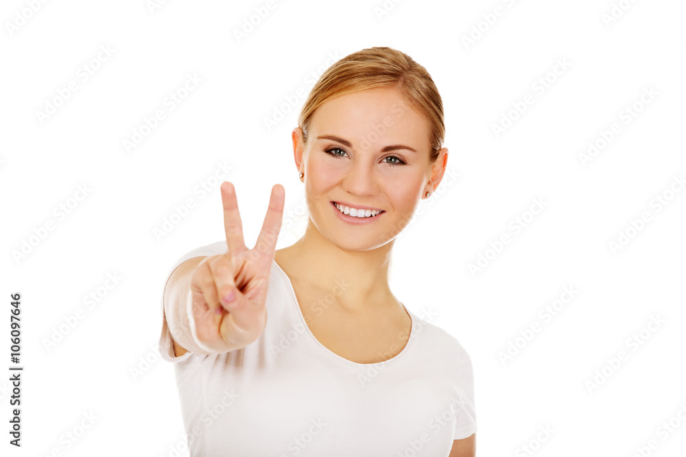 Smiling young woman showing the victory sign Smiling young woman showing the victory sign