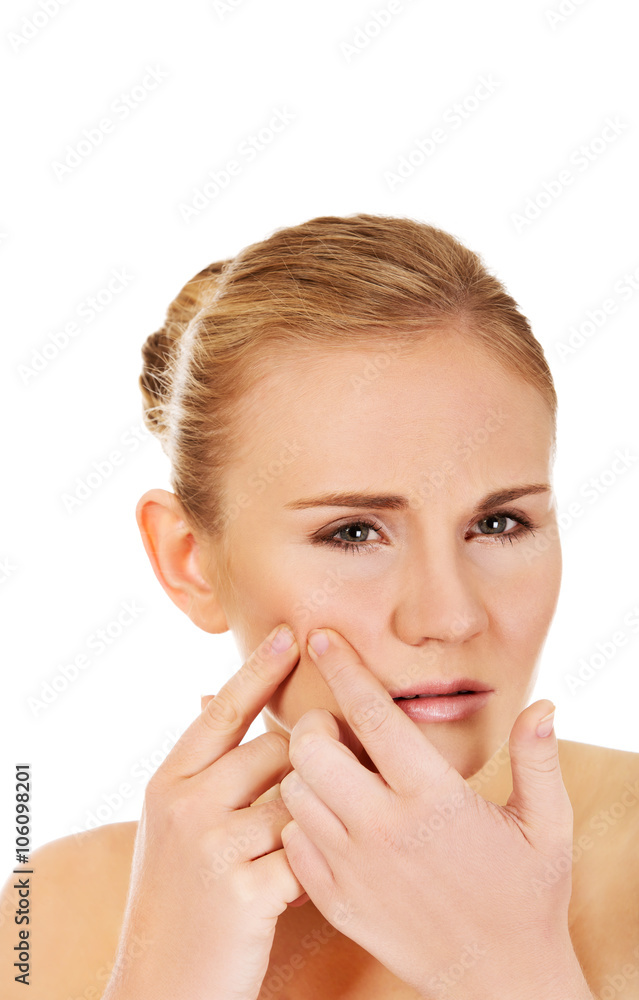 Unhappy young woman squeezing pimple on face Unhappy young woman squeezing pimple on face